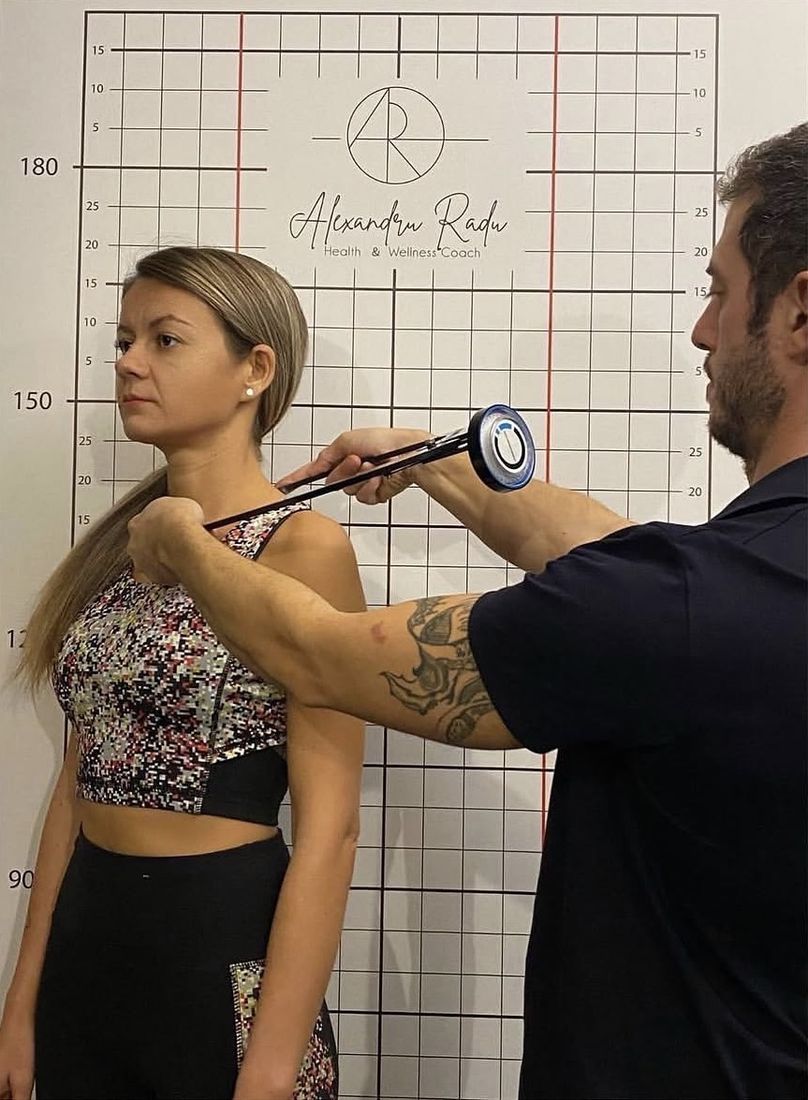 Alexandru measuring a client's shoulder position against the posture grid