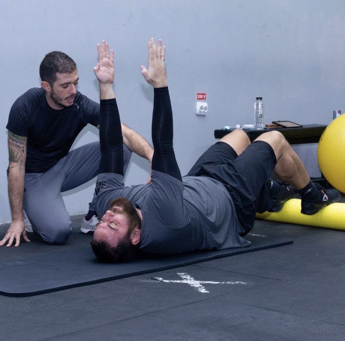 Alexandru coaching a client through a corrective exercise on the floor